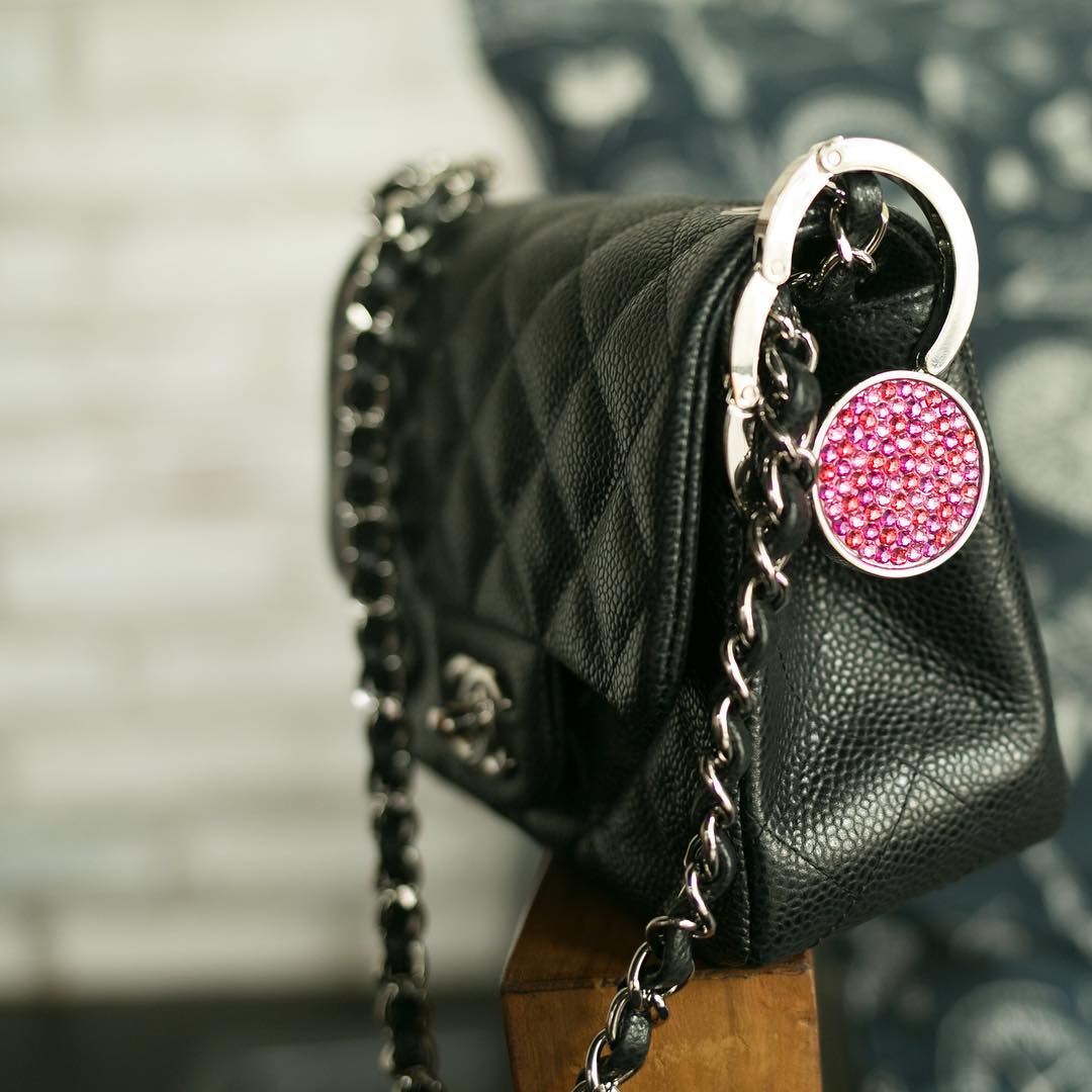 A crystal Luxe Link hook clipped to a black quilted shoulder bag