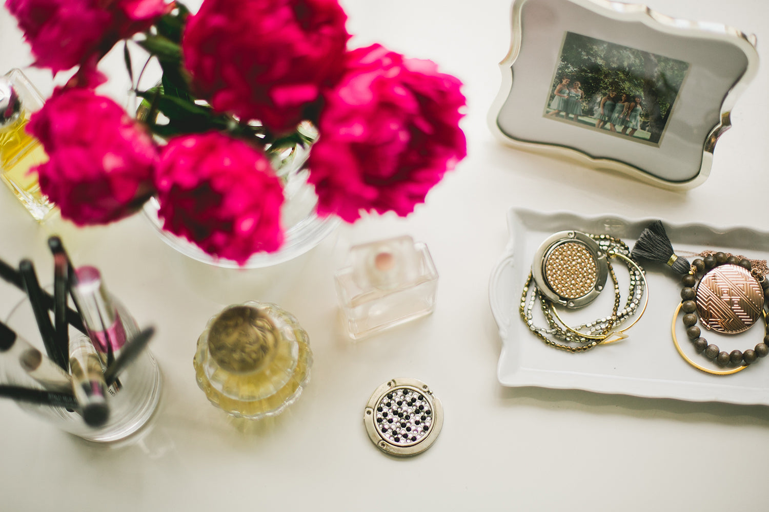 Peonies and jewelry on a vanity with a Luxe Link charm